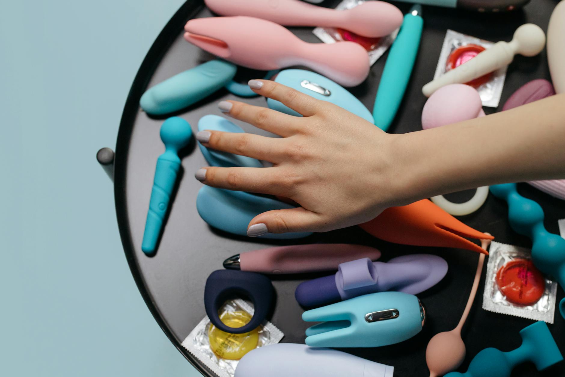 Een hand die een oranje vibrator vasthoudt tegen een minimalistisch paarse achtergrond, met aandacht voor gevoelige sensualiteit