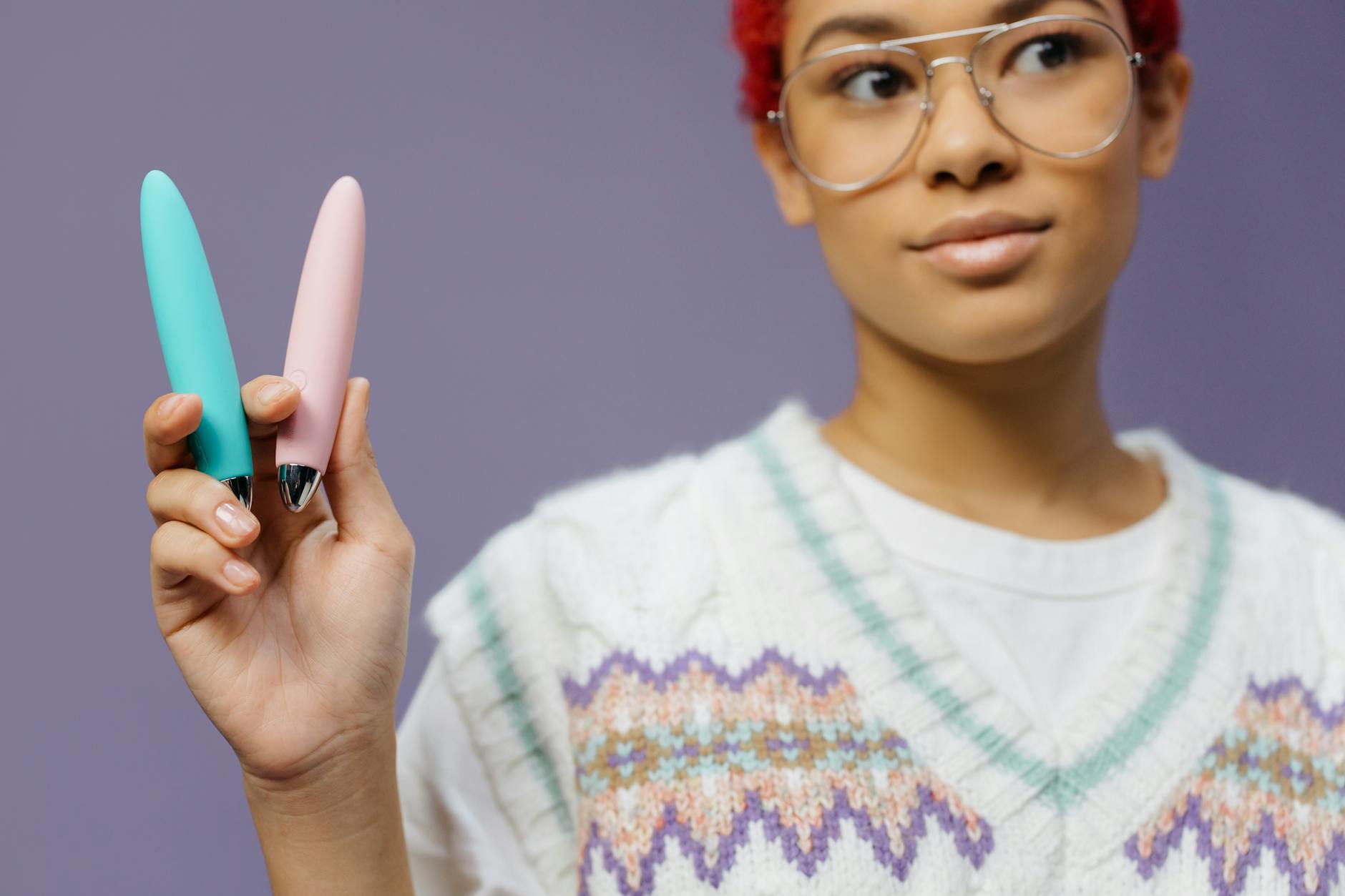 Handen houden samen een blauwe clitorale vibrator vast tegen een paarse achtergrond