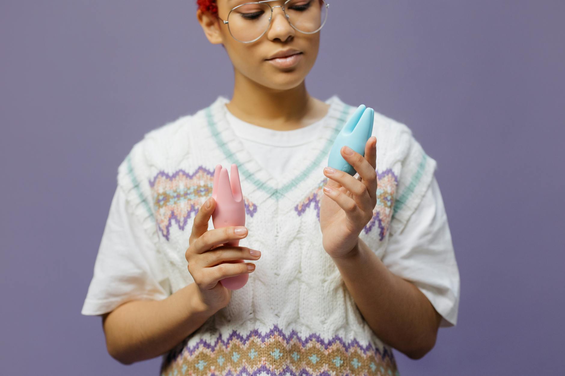 Een vrouw met bril houdt gekleurde vibrators vast en denkt na over haar lichaam en gewenning