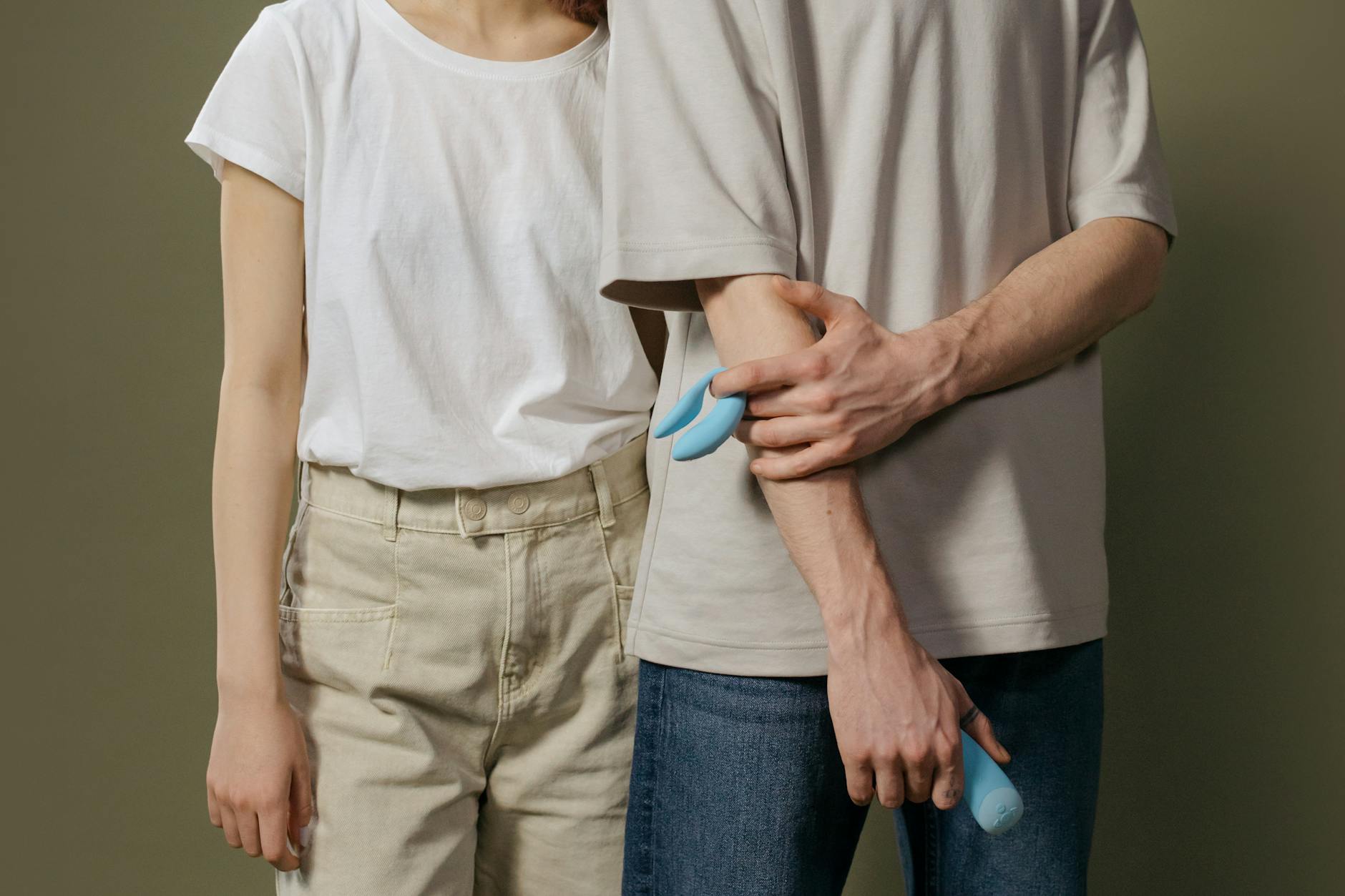 Een jong stel staat samen binnen, met een blauwe vibrator, symbool van moderne intimiteit