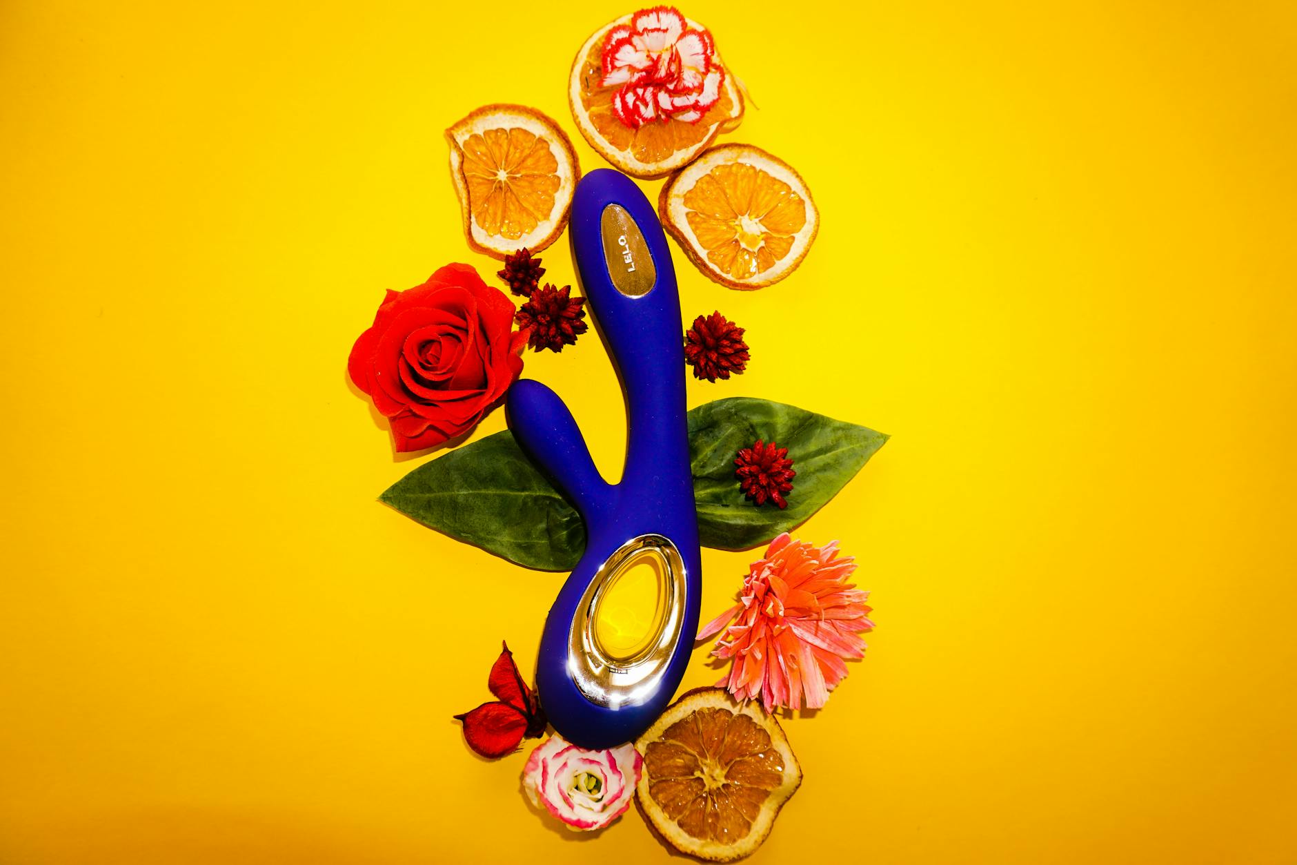 Lem citroenvibrator omgeven door bloemen en citroenschijfjes op gele achtergrond