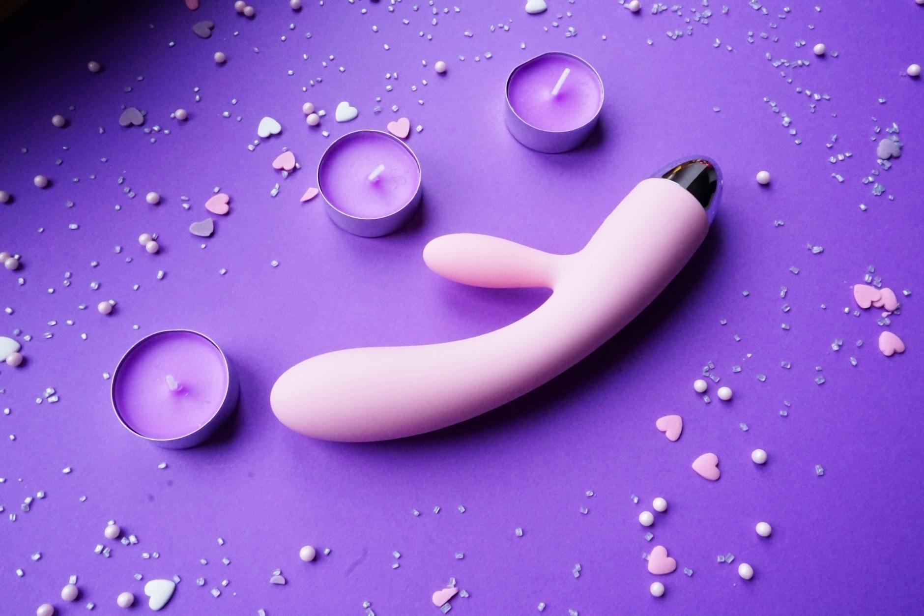 Roze citroenvibrator op paarse achtergrond met hartvormige confetti voor een romantische sfeer